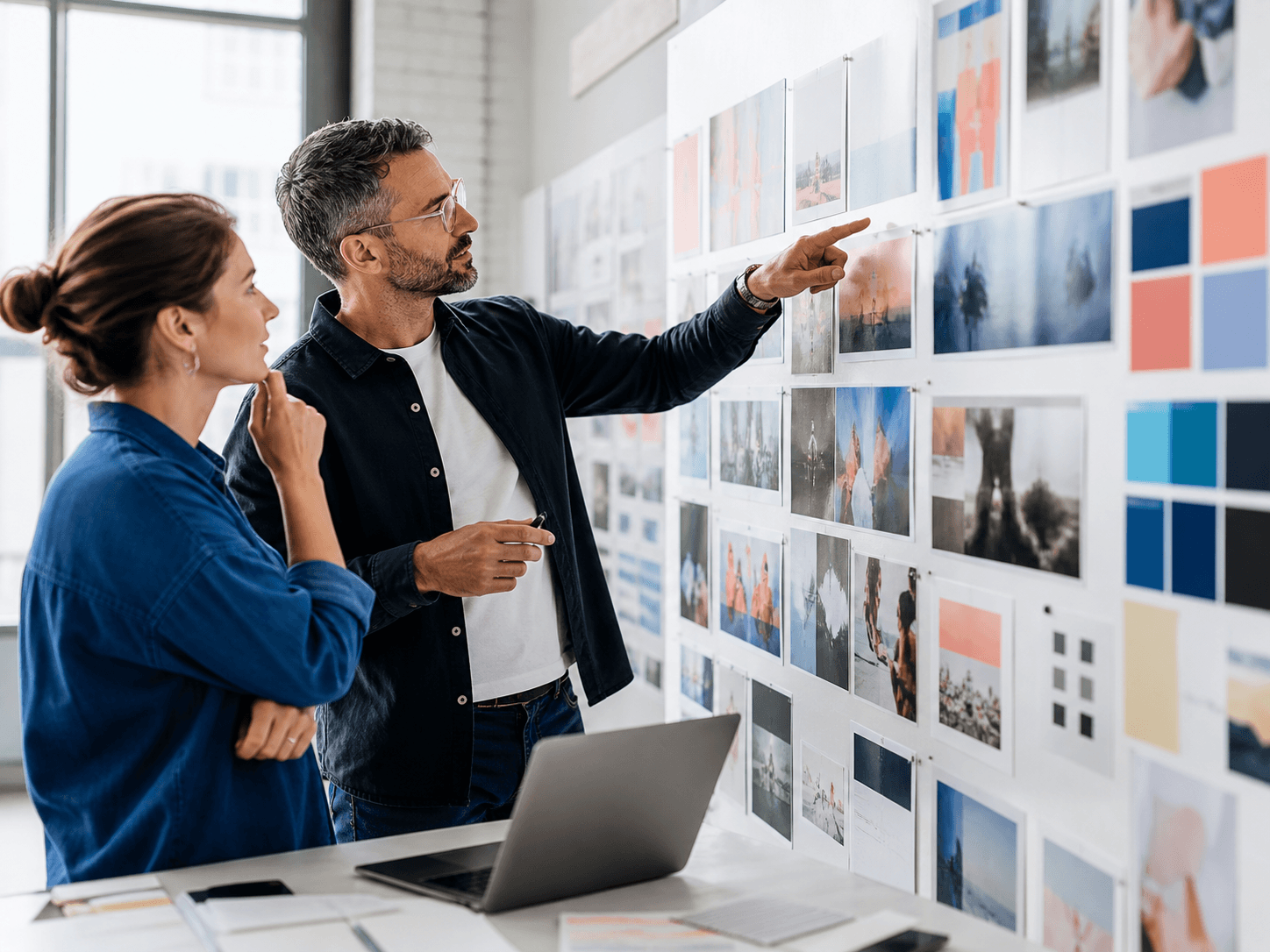 Two strategists reviewing a wall of competitor creative references